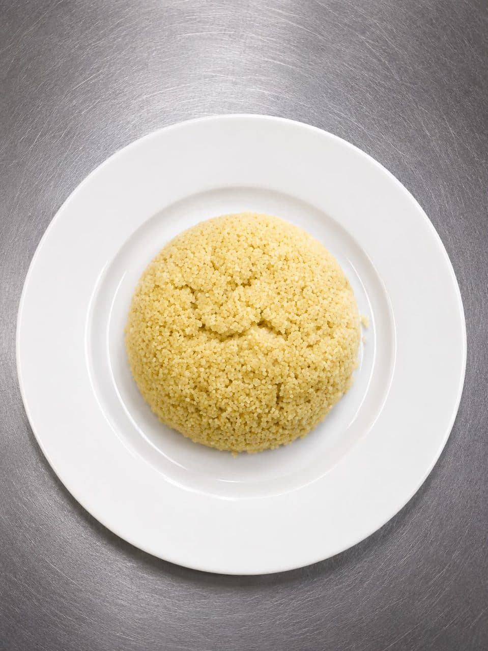 Portion d'attiéké, semoule de manioc, dressée dans une assiette blanche
